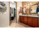 Bathroom with dual sinks, vanity and mirrors, complemented by wood-look flooring and a walk-in closet at 20962 W Thomas Rd, Buckeye, AZ 85396