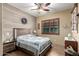 Comfortable bedroom featuring wood paneling, a ceiling fan, and a window with wooden shutters at 20962 W Thomas Rd, Buckeye, AZ 85396