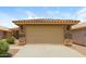 Attached two-car garage with neutral door and stone accents, complemented by a tile roof at 23162 W Lasso Ln, Buckeye, AZ 85326