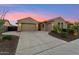 Inviting home featuring a spacious three-car garage and desert landscaping under a colorful sky at 27308 N 56Th Dr, Phoenix, AZ 85083