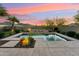 Tranquil backyard oasis with a sparkling pool, water feature, and lush landscaping at sunset at 27308 N 56Th Dr, Phoenix, AZ 85083
