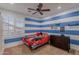 Bedroom is decorated with blue and white striped walls, a ceiling fan, and a window at 27809 N Silverado Ranch Rd, Peoria, AZ 85383