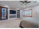 Carpeted bedroom featuring a ceiling fan, fireplace, TV, built-in shelves and natural light from the large window at 27809 N Silverado Ranch Rd, Peoria, AZ 85383