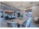 Open-concept dining area flows to the kitchen, featuring wood floors, a rustic dining table and contemporary lighting at 27809 N Silverado Ranch Rd, Peoria, AZ 85383