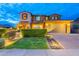 Well-lit front exterior features lush landscaping, an attached garage, and a tiled driveway at 27809 N Silverado Ranch Rd, Peoria, AZ 85383