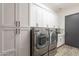 Well-equipped laundry area with front loading washer/dryer, ample storage cabinets, and decorative backsplash at 27809 N Silverado Ranch Rd, Peoria, AZ 85383