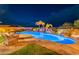 Stunning backyard pool at night with rock features, waterfall, and desert landscaping illuminated under a starry sky at 27809 N Silverado Ranch Rd, Peoria, AZ 85383