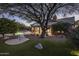 The patio area features desert landscaping, an inviting pool, and a grassy seating area under a beautiful tree at 28897 N 94Th Pl, Scottsdale, AZ 85262