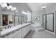 Bathroom with dual sinks, vanity lighting, shower, a jetted tub, and an enclosed walk-in closet at 28897 N 94Th Pl, Scottsdale, AZ 85262