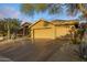 Tan home boasts a three-car garage, mature trees, and desert landscaping at 28897 N 94Th Pl, Scottsdale, AZ 85262