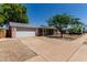 Charming single-story home featuring a wide driveway, two-car garage, and mature trees, set against a clear blue sky at 3030 E Shangri La Rd, Phoenix, AZ 85028