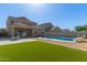 An expansive backyard featuring lush artificial turf, a sparkling pool, and a covered patio at 3113 N 303Rd Dr, Buckeye, AZ 85396