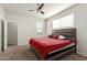 Bedroom with a bed with a red comforter, ceiling fan, and a view of the ensuite bathroom at 3113 N 303Rd Dr, Buckeye, AZ 85396