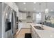 Bright kitchen boasts stainless steel appliances, white cabinetry, and a large quartz island with pendant lighting at 32567 N 133Rd Ave, Peoria, AZ 85383
