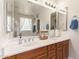 Well-lit bathroom with a double sink vanity, large mirrors and tub with decorative window at 3381 E Canary Way, Chandler, AZ 85286
