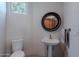 Bright powder room featuring a stylish round mirror and a charming pedestal sink at 3405 E Knox Rd, Phoenix, AZ 85044