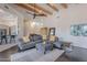 Open-concept living room with wood beam ceilings, dark wood floors, and grey sectional sofa at 3405 E Knox Rd, Phoenix, AZ 85044