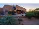 Spacious backyard featuring a fence, a spiral staircase, lush vegetation, and desert landscaping at sunset at 5520 E Desert Forest Trl, Cave Creek, AZ 85331