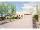View of the beige stucco home with a paver driveway, desert plants and a Saguaro cactus at 5520 E Desert Forest Trl, Cave Creek, AZ 85331