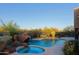 Backyard swimming pool with a rock waterfall, mature desert landscaping, spa, and patio at 5520 E Desert Forest Trl, Cave Creek, AZ 85331