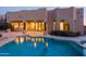Backyard pool and patio area with desert landscaping; lights from interior reflect on pool surface at 5520 E Desert Forest Trl, Cave Creek, AZ 85331