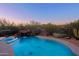 Backyard pool with rock waterfall, mature desert landscaping, and a mountain view beyond fence at 5520 E Desert Forest Trl, Cave Creek, AZ 85331