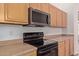 Modern kitchen with stainless steel microwave, range, and wood cabinets offers functionality at 6787 W Saddlehorn Rd, Peoria, AZ 85383