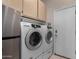 Well-equipped laundry room with stainless steel fridge and white washer and dryer set at 7762 E Russell Cir, Mesa, AZ 85207