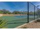 Well-maintained tennis court with a green fence surrounded by desert landscaping and trees at 7762 E Russell Cir, Mesa, AZ 85207
