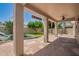 Inviting covered patio featuring stone flooring, ceiling fan, and a beautifully landscaped backyard with mature trees at 9563 E Keats Ave, Mesa, AZ 85209