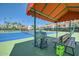 Tennis court with covered seating area, equipment, and views of the surrounding community at 9707 E Mountain View Rd # 1408, Scottsdale, AZ 85258