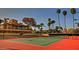 Spacious tennis court with a red surface and a view of a building and palm trees at 9707 E Mountain View Rd # 1408, Scottsdale, AZ 85258