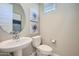 Well-lit powder room with a pedestal sink, modern toilet, and decorative artwork at 10132 E Ursula Ave, Mesa, AZ 85212