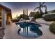 Inviting backyard pool featuring a waterfall, built-in grill, and lush landscaping, perfect for outdoor living and entertaining at 12754 E Laurel Ln, Scottsdale, AZ 85259