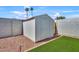 Backyard featuring a white storage shed with artificial grass and gravel at 12826 N 29Th St, Phoenix, AZ 85032