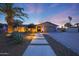 Home exterior featuring desert landscaping, dramatic lighting, a concrete walkway, and a spacious three car garage at 14014 N 57Th Way, Scottsdale, AZ 85254