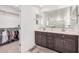 This Primary bath features dual sinks, a vanity, a large mirror, and a walk-in closet at 14253 W El Cortez Pl, Surprise, AZ 85387