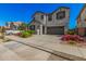Two-story home featuring a well-manicured front yard with colorful flower beds, covered porch, and large garage at 14253 W El Cortez Pl, Surprise, AZ 85387
