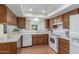 Well-lit kitchen featuring wood cabinets, white appliances and countertops, and a window over the sink at 1704 E Hackamore St, Mesa, AZ 85203