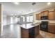 Open kitchen and living area with island, wood cabinets, tile floor and stainless appliances at 17789 W Bridger St, Surprise, AZ 85388
