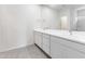Bright bathroom boasting dual sinks, a large mirror, and modern fixtures over gray ceramic tile flooring at 2181 N 211Th Dr, Buckeye, AZ 85396