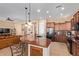 Open kitchen with stainless steel appliances, granite counters, island with bar seating, and view to living room at 29159 N 128Th Ln, Peoria, AZ 85383
