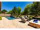 Resort-style backyard featuring a swimming pool, mature trees, and a cozy fire pit area at 3081 E Desert Broom Pl, Chandler, AZ 85286