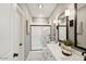 Modern bathroom featuring double sinks, black hardware, white marble tile, and a glass enclosed shower at 3913 S 233Rd Ln, Buckeye, AZ 85326