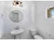 Well-lit powder room featuring a pedestal sink, round mirror, and a window at 4527 E Gagarinite Ln, San Tan Valley, AZ 85143