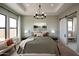 Bright bedroom featuring a tray ceiling, bedside lamps, and decorative barn door at 477 E Aurora Dr, San Tan Valley, AZ 85140