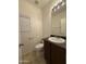 A neat half-bathroom features a sink, toilet, mirror, cabinet, and a window that provides soft natural light at 6341 W Valencia Dr, Laveen, AZ 85339
