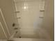 This bathtub features bright white tile and soap shelves at 6341 W Valencia Dr, Laveen, AZ 85339