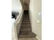 Stairway with carpet runner and white railing, next to thermostat at 6341 W Valencia Dr, Laveen, AZ 85339