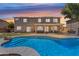 A spacious backyard with a sparkling blue pool, covered patio, and green lawn at 7129 S Stadium Way, Gilbert, AZ 85298